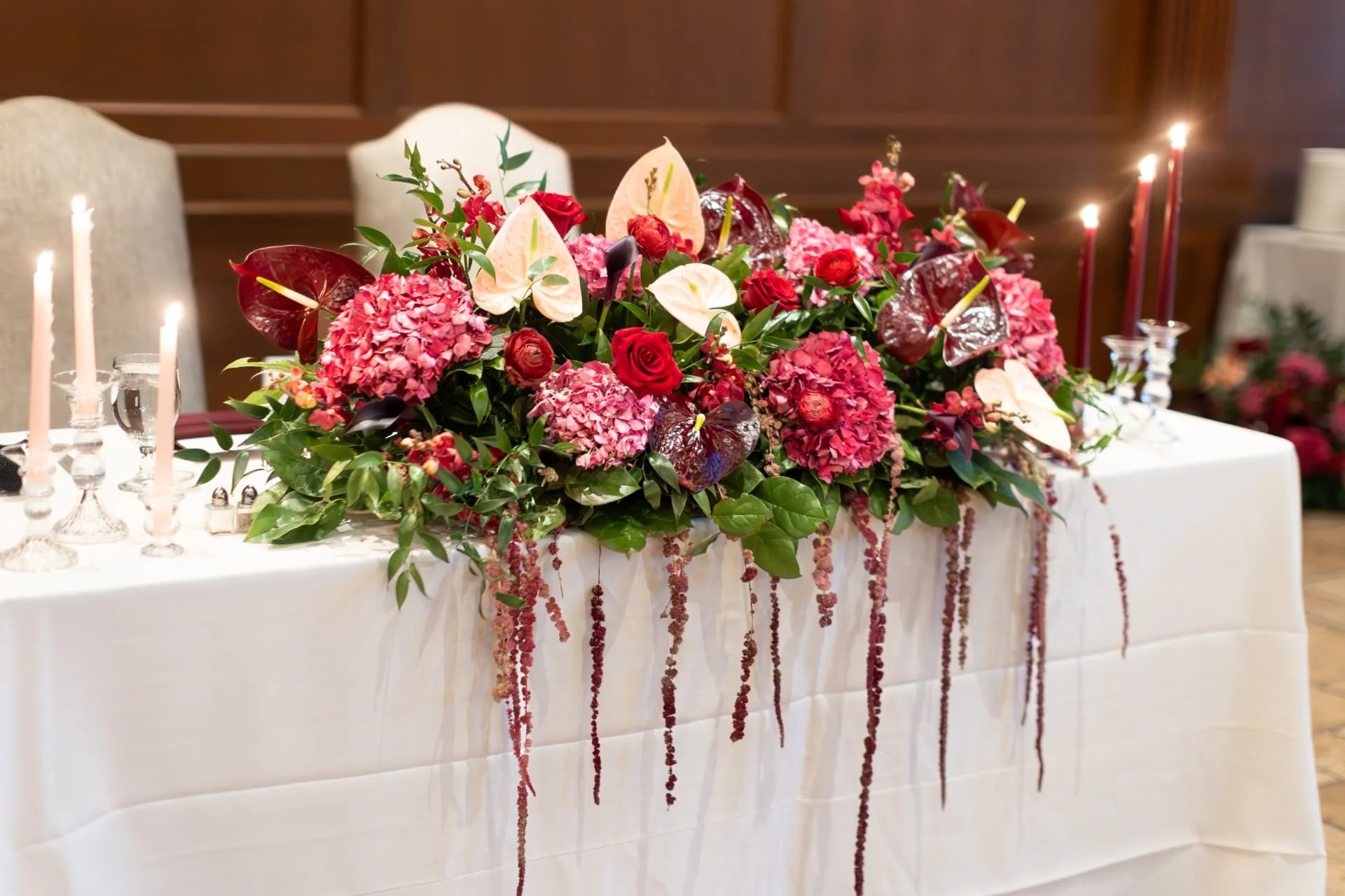 Candlelit sweetheart table with red and pink floral runner at a romantic Arizona wedding reception
