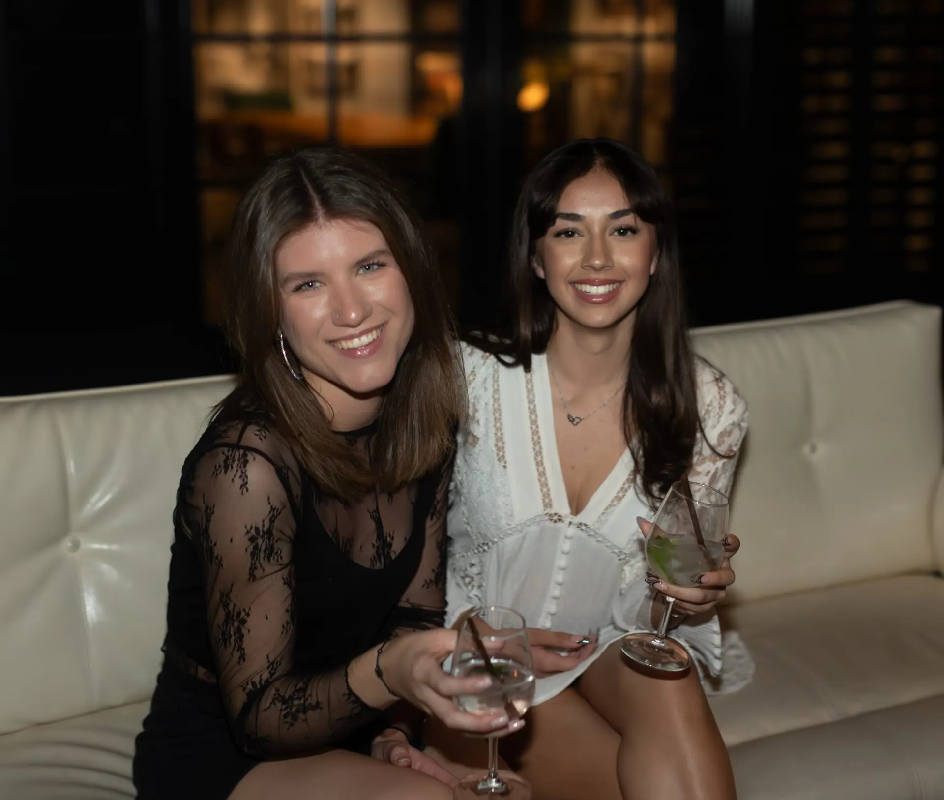 Bride and her best friend on a white leather couch at a Scottsdale bachelorette night out