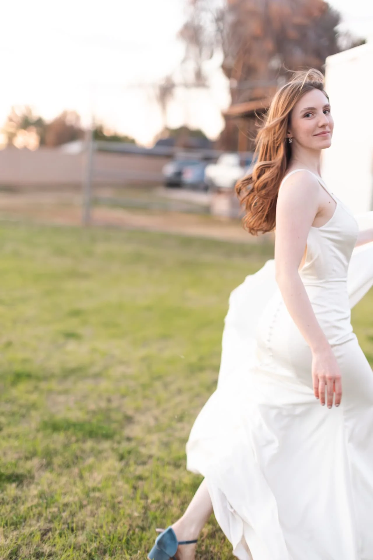 Bride running across a lawn at golden hour, train and hair in motion — romantic Arizona wedding photography in Scottsdale