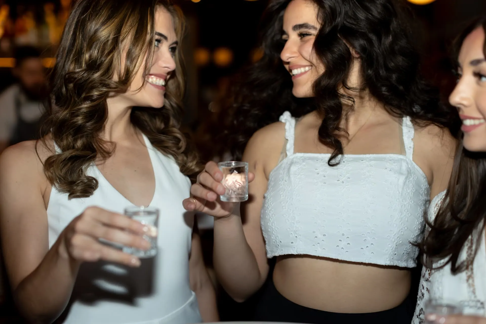 Bachelorette friends taking a shot together at a dim Scottsdale bar