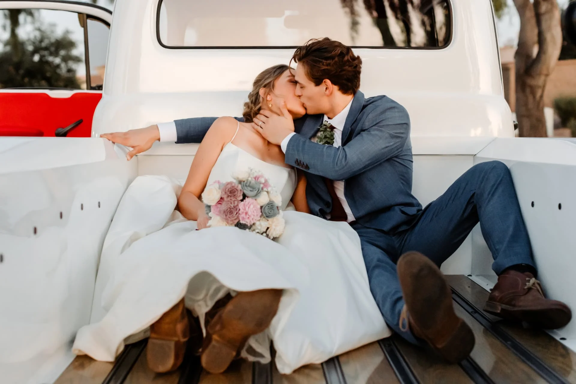 Bride and groom kissing in the bed of a white vintage truck at golden hour — Arizona wedding photography near Scottsdale