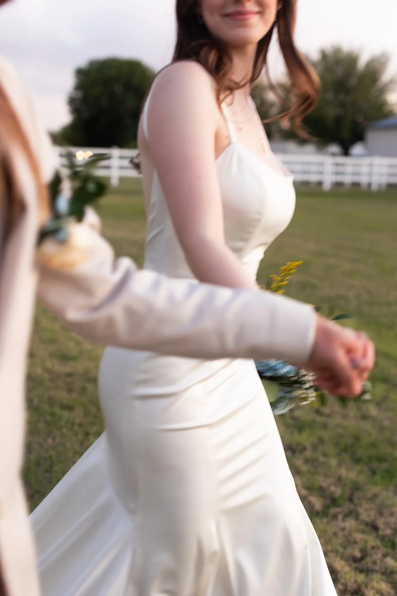 Groom leading his bride by the hand across a field at dusk with soft motion blur — documentary Arizona wedding photographer